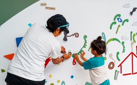 Parent and child using magnets on magnet wall