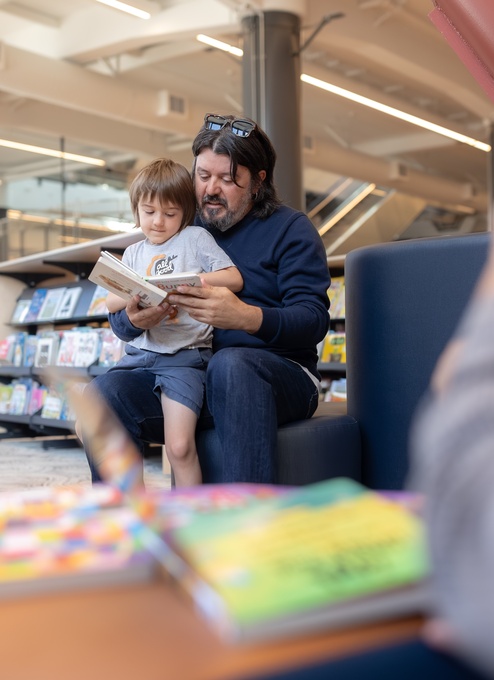 man with child on lap, reading a book