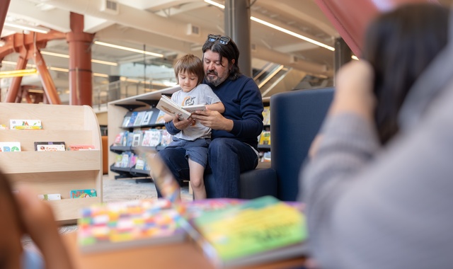 man with child on lap, reading a book